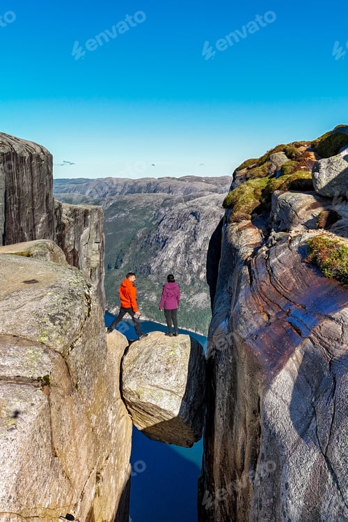 Preview: Adventurous Hikers Gazing Over Kjeragbolten Majestic Cliff Edge in Norway