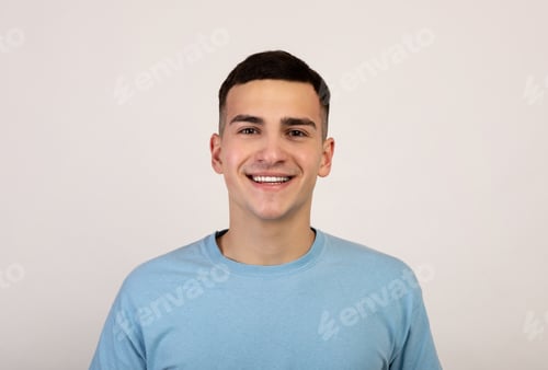 Preview: Portrait of handsome Caucasian young man in casual clothes smiling and looking at camera over light