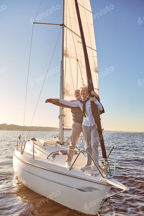 Preview: Boat tour. Full length of a happy senior couple stretching hands out against the sky