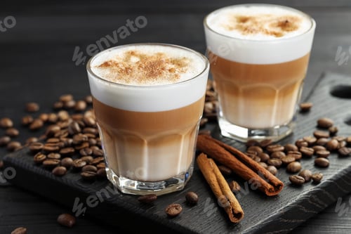 Preview: Tasty latte macchiato in glasses, coffee beans and cinnamon on black wooden table, closeup