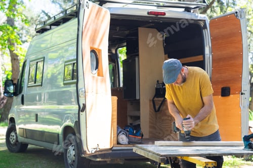 Preview: Man sanding wood with an electric sander customizing a camper van