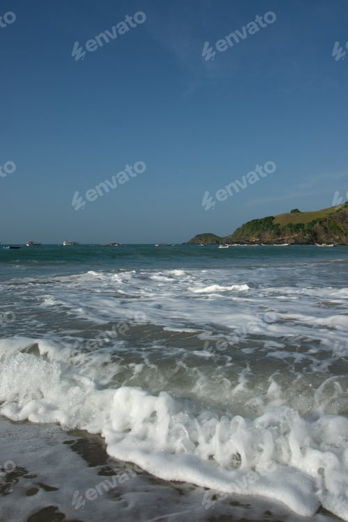 Preview: Waves breaking on the shore of the beach. Sea foam. Wet sand. Stones on the beach. Caribbean tropica