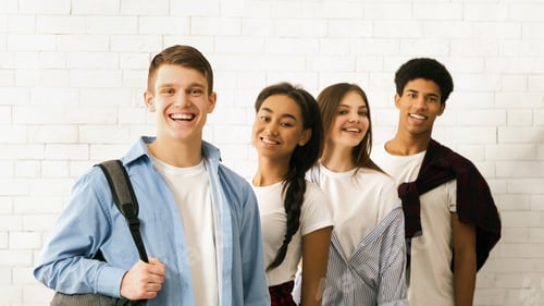 Preview: Four Happy Teenagers Standing Together Against White Brick Wall Background
