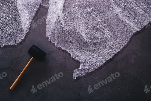 Preview: Flat lay of a hammer and bubble wrap