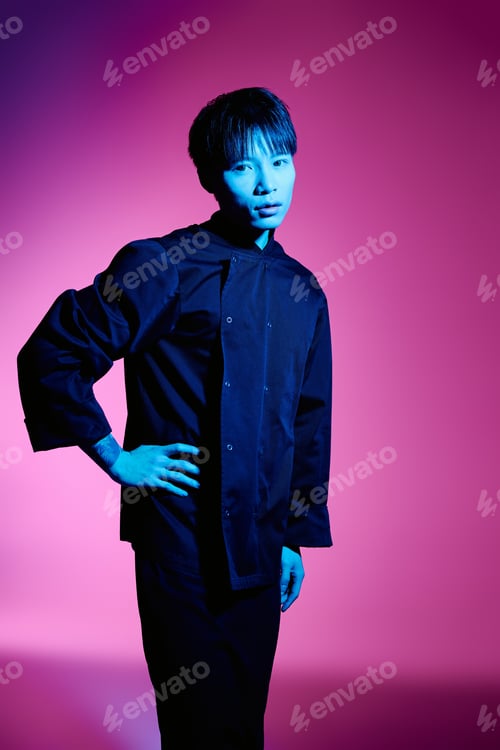 Preview: Stylish asian man posing against a vibrant pink and blue backdrop in a trendy outfit