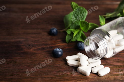 Preview: Bottle with vitamin pills and blueberries on wooden table. Space for text