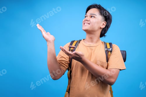 Preview: Positive Young Asian Man Carry Backpack Stuff Mat Showing Offering Gesture To Copy Space
