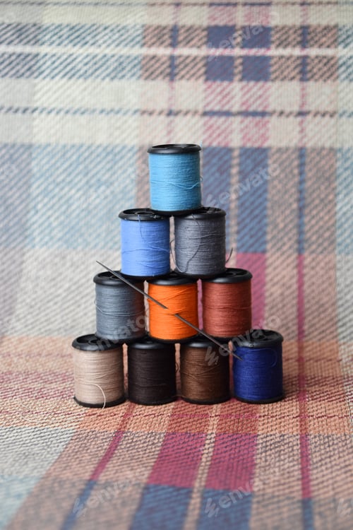 Preview: stack of yarn spools or bobbins on woven fabric background