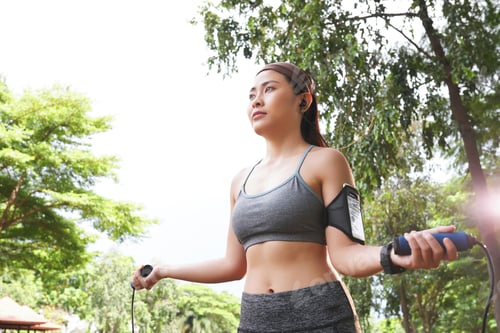 Preview: Young woman jumping rope in green park