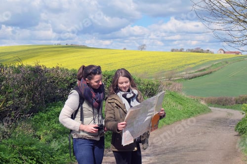 Preview: Two young women standing on country road, looking at map