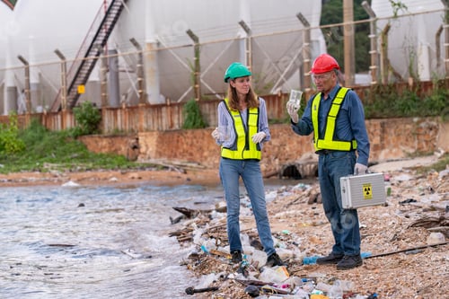 Preview: Environmental scientists or workers, wearing safety helmets and gloves, examining waste materials al