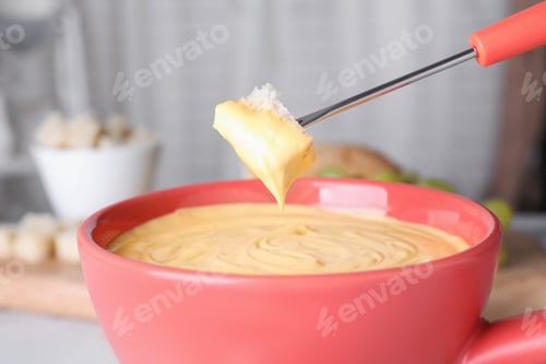 Preview: Dipping bread into pot with cheese fondue, closeup