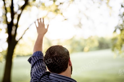 Preview: Closeup shot from behind of a male with his hand up and a blurred background