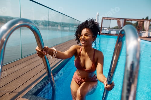 Preview: Young happy black woman getting out of the swimming pool.