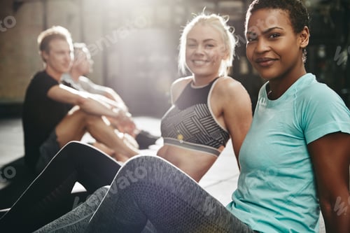 Preview: Smiling women sitting on a gym floor after working out