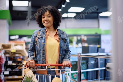 Preview: Happy mature woman shopping at supermarket and looking at camera.