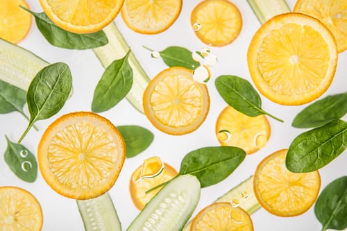 Preview: fresh orange slices with green spinach leaves and cucumbers on grey background