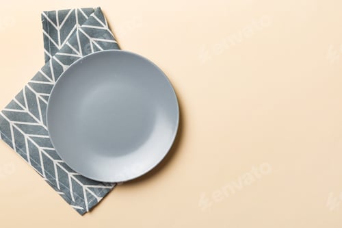 Preview: Top view on colored background empty round gray plate on tablecloth for food. Empty dish