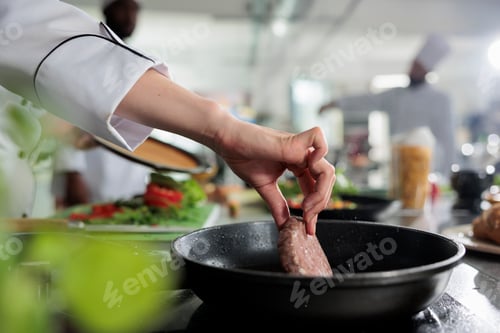 Preview: Close up of master chef hands cooking beef patty in hot pan while cooking gourmet dish for dinner