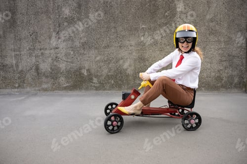 Preview: Funny businesswoman driving retro pedal car outdoor