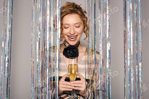 Preview: A young woman joyfully wraps gifts while celebrating with a sparkling drink in a festive atmosphere