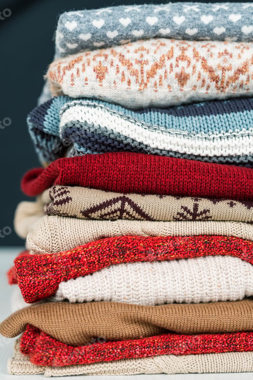 Preview: Stack of new woolen and cotton sweaters and jumpers prepared for cold days