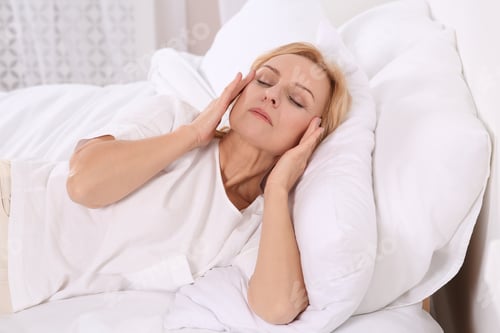 Preview: Woman suffering from headache in bed at home. Hormonal disorders