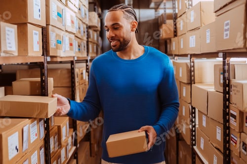 Preview: Warehouse worker checking inventory and picking up cardboard box