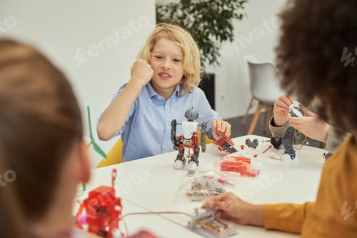 Preview: Lively little caucasian boy looking emotional while sitting at the table and examining details of