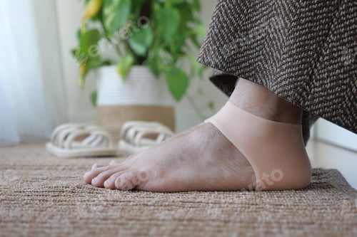 Preview: Foot wearing a support band on a rug in a bright room
