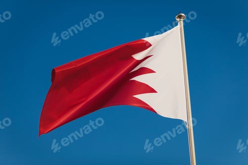 Preview: Red and white Bahrain flag, capital Bruxelles. National flag on flagpole in front of blue sky