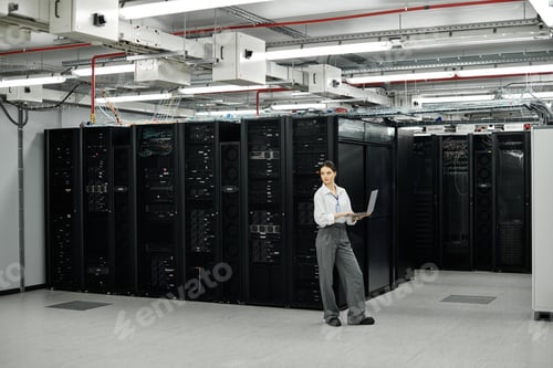 Preview: In a modern server room, a woman in a white shirt manages computer systems with focus and skill.