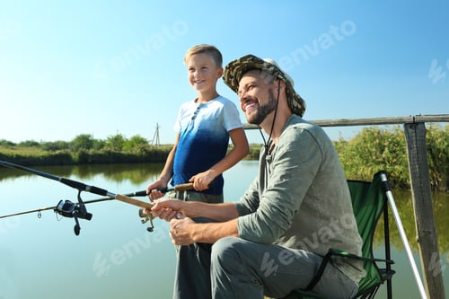 Preview: Father and son fishing together on sunny day