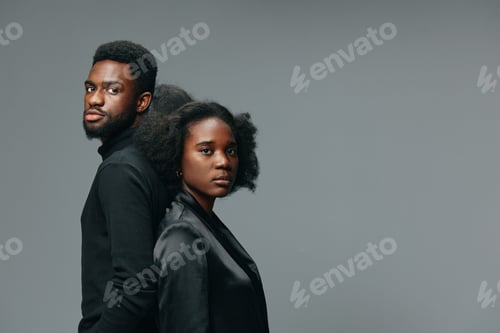 Preview: Portrait of a stylish black couple standing back to back, showcasing confidence in modern attire
