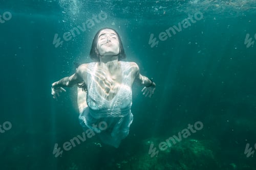 Preview: A young woman will dive with a white dress swimming, underwater image, summer
