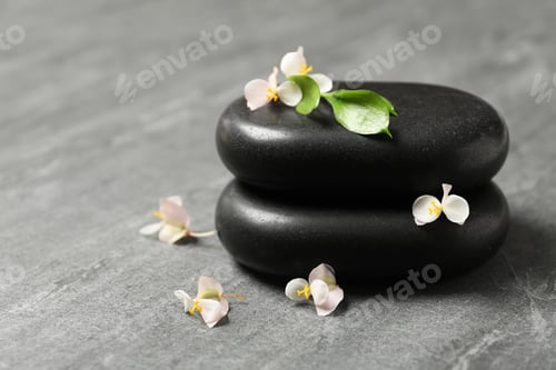 Preview: Stacked spa stones with flowers and leaves on table. Space for text