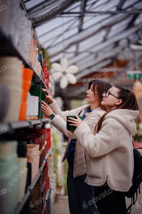 Preview: Women Choosing Ceramic Planters in Garden Store Aisle