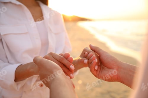Preview: Lovely couple holding hands on beach at sunset, closeup