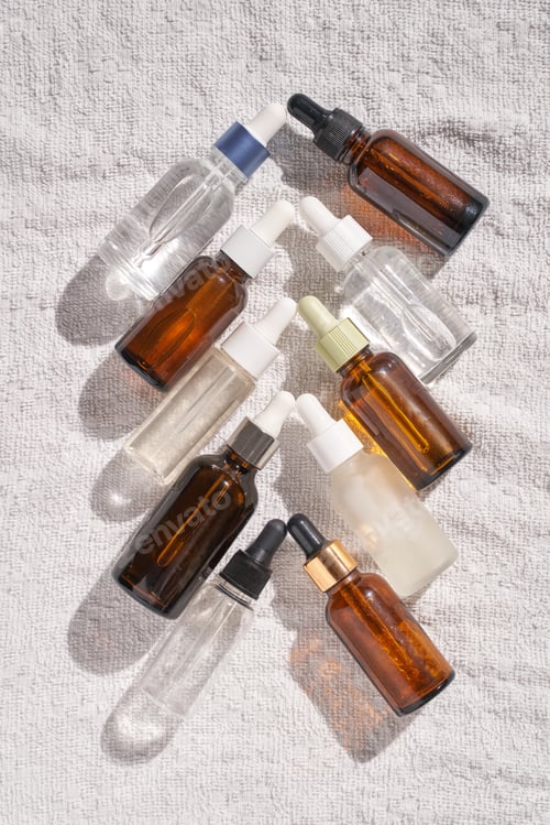 Preview: Assorted cosmetic serum bottles flat lay on towel skincare beauty background with natural light
