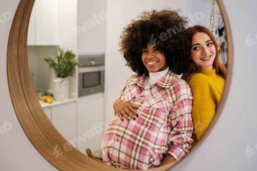 Preview: Couple of young girls in the mirror proud of their pregnancy and life together - motherhood concept