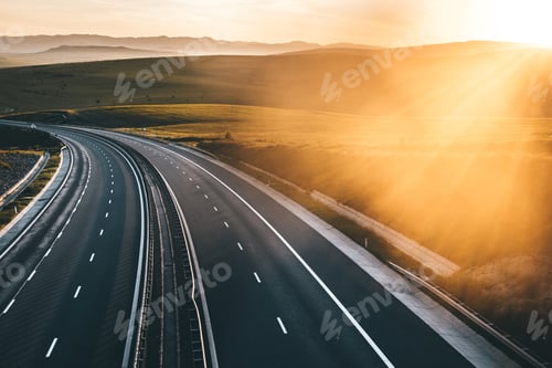 Preview: Empty highway with a beautiful sunset at golden hour with surrounding mountains