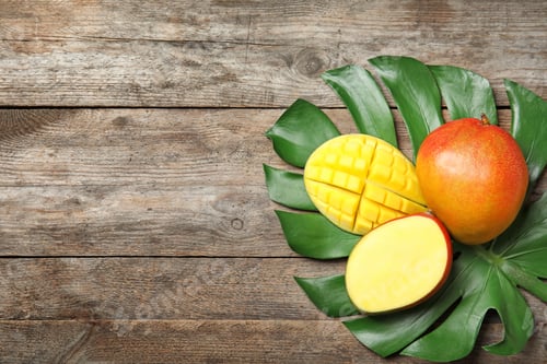 Preview: Flat lay composition with ripe mangoes, monstera leaf and space for text on wooden background