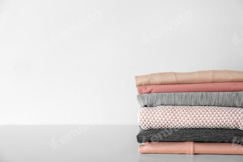 Preview: Stack of clothes on table against light background