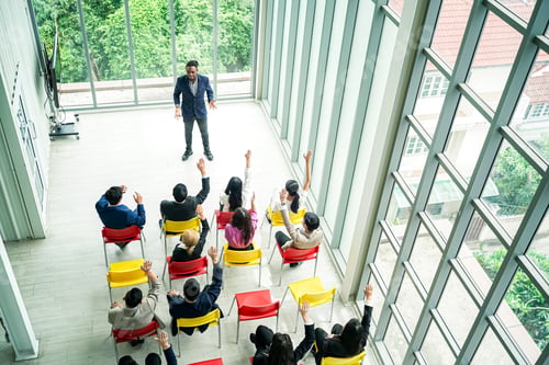 Preview: Raised up hands of large group in seminar class room to agree with speaker at conference seminar