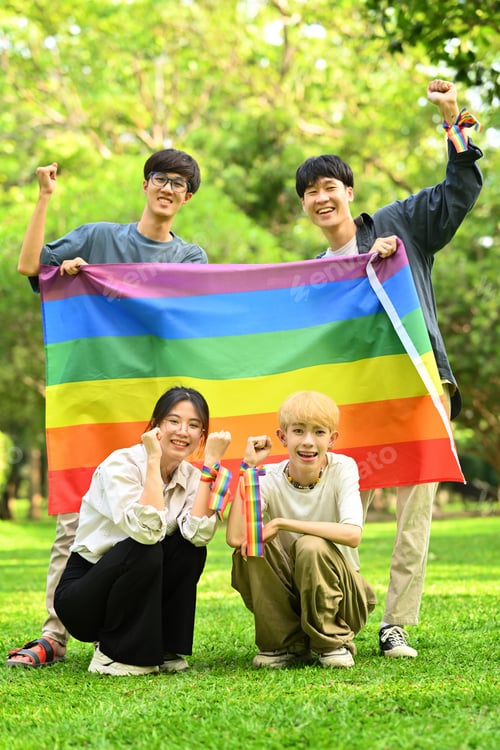 Preview: Image of young people with LGBTQ pride flag, standing in public park.