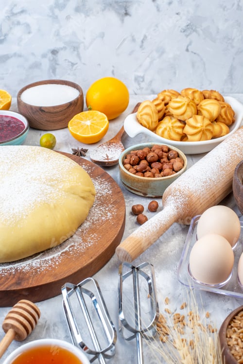 Preview: Side view of raw pastry on round board and set of various foods grater on ice background