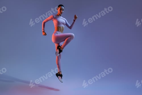 Preview: Sporty woman in sportswear jumping on studio background. Sport and healthy lifestyle