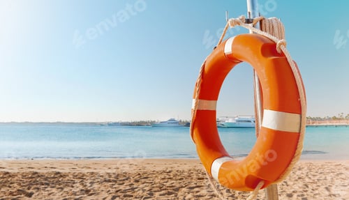 Preview: Lifebuoy circle. Scenic view of red and white lifebuoy on post on seaside beach. Scenery landscape o