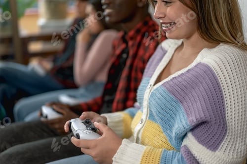 Preview: Young multiracial teenagers playing online video game console at home
