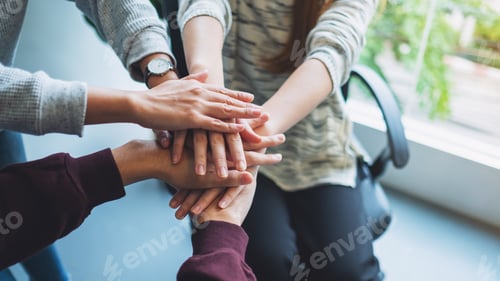 Preview: Closeup image of business team standing and joining their hands together in office